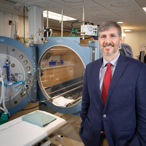 Dr. Kevin Hatton, the division chief of Anesthesiology Critical Care Medicine at UK HealthCare, poses next to the hyperbaric oxygen treatment chamber.
