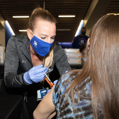 Photo by Mark Cornelison of a woman receiving a covid vaccine shot in her arm.