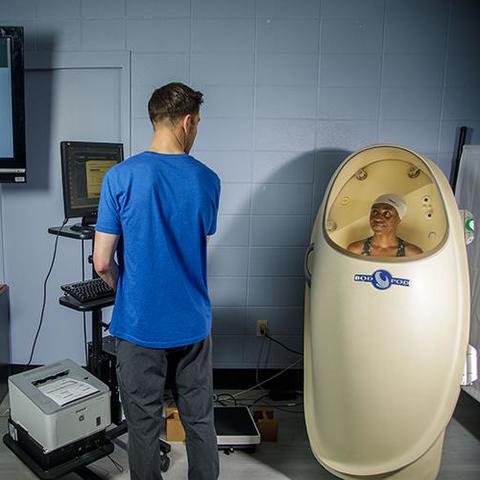 Student (left) standing next to the Bod Pod (right)