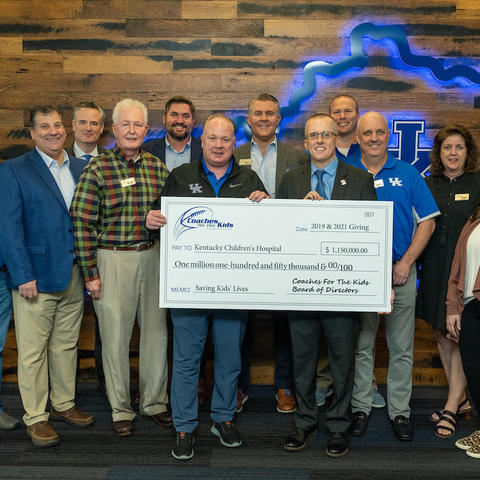 image of Coach Stoops with the Coaches for the Kids Board of Directors presenting a check to Dr. Scottie Day