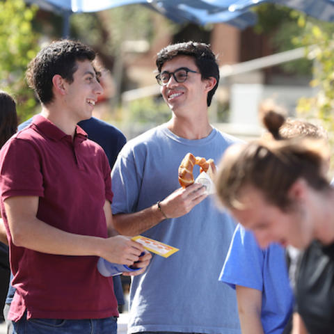 Students eating food and laughing at an event