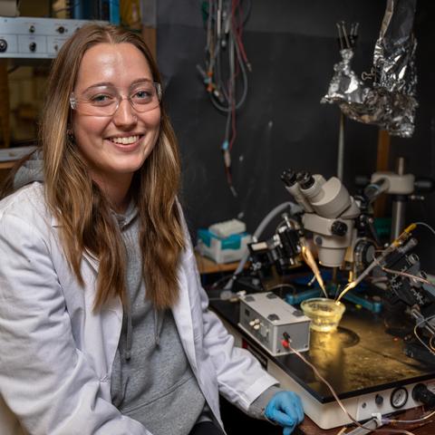 UK student Kaitlyn Brock seated next to a piece of lab equipment