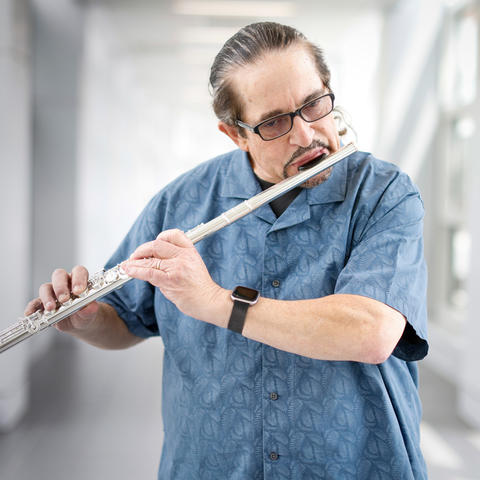 White man in light blue shirt playing flute