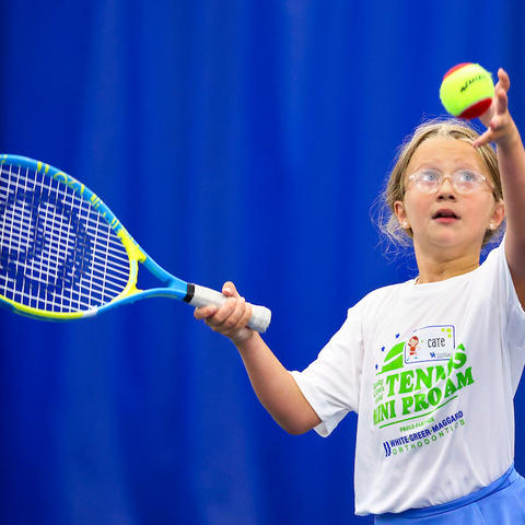 young child with tennis racket prepares to hit a tennis ball