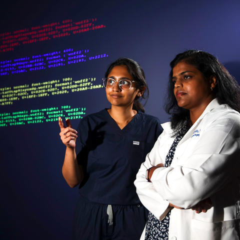 Two women pointing at digital text