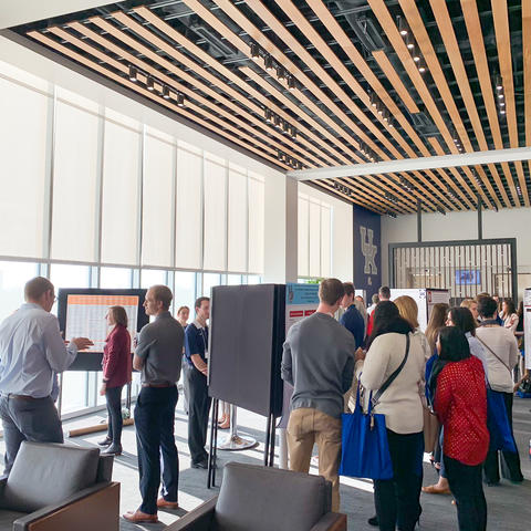 People standing and looking at research project boards. 
