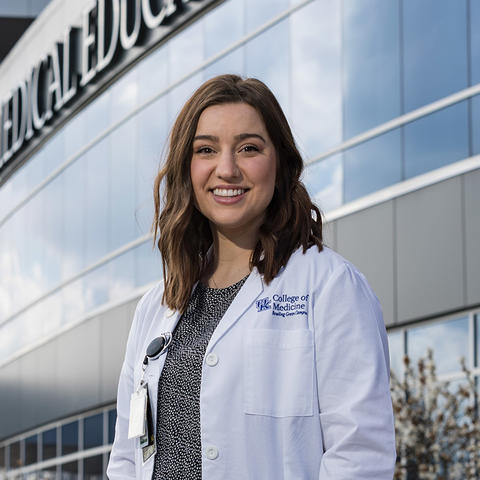 Young woman with brown hair wearing a white doctor's coat