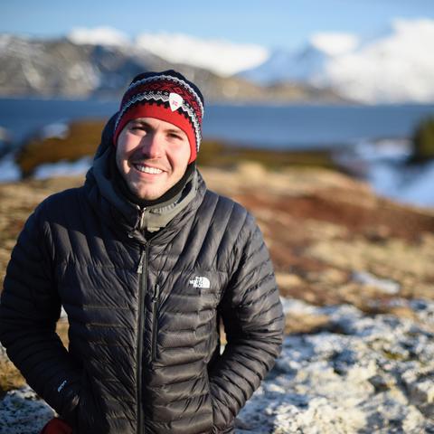 photo of Benjamin Troupe with water and snow covered mountains behind him