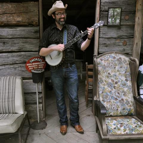 photo of Brett Ratliff on porch with banjo