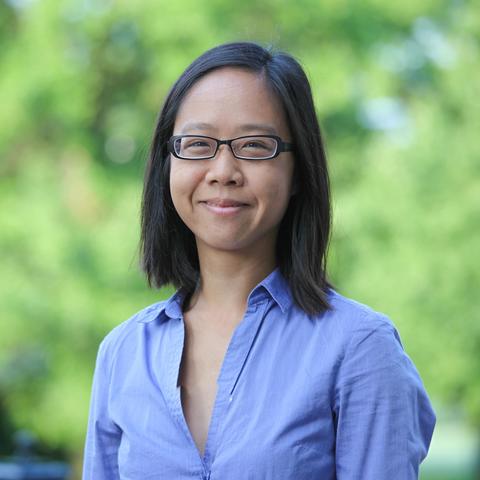 Woman with black hair, wearing eyeglasses and a blue shirt