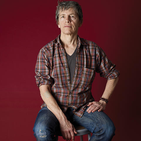 photo of Eileen Myles on stool with red background by Catherine Opie