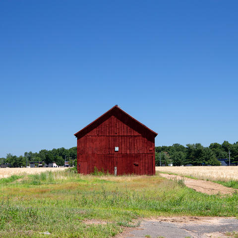 image of a red barn in the daytime with forest in the background