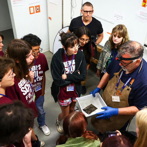 Various high school students gathered around an instructor, who is demonstrating a skill at Governor's School for the Arts