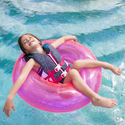 little girl in pink tube floating in pool