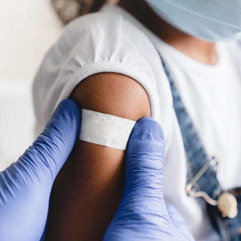 Photo of a child with a band-aid on arm after receiving a shot