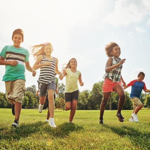 Five children running outside on the grass