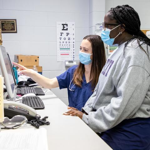 Image of medical students looking at a computer screen in a medical clinic.
