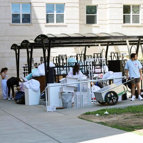 Students move belongings and furniture outside a residence hall during campus move-in.