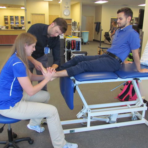 Ryan shows Morgan how to adjust a patient's foot