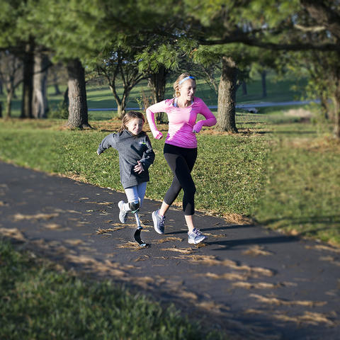 Photo of Carson Swartz running with Katie Eddington, who has a prosthetic leg