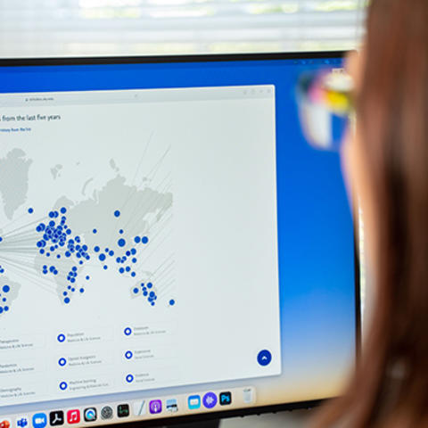 Woman looks at Scholars at UK portal on computer screen with world map