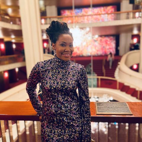 photo of Makeda Hampton inside the Met with a trademark chandelier behind her