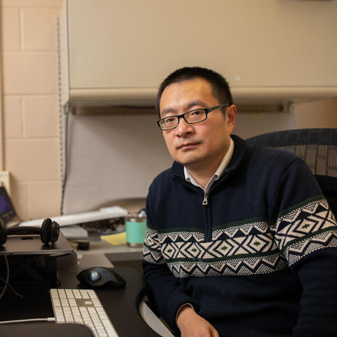 Photo of Qing Shao Next to Computer