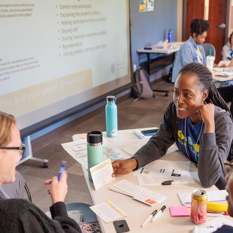 Two students and one professor sitting at a table holding a discussion 