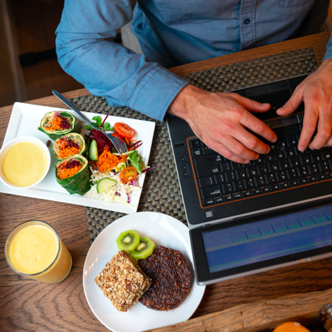 Man working at computer with food. 