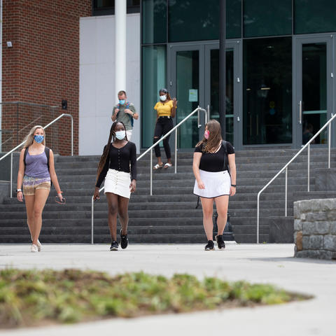 three students wearing masks for covid protection walking on campus