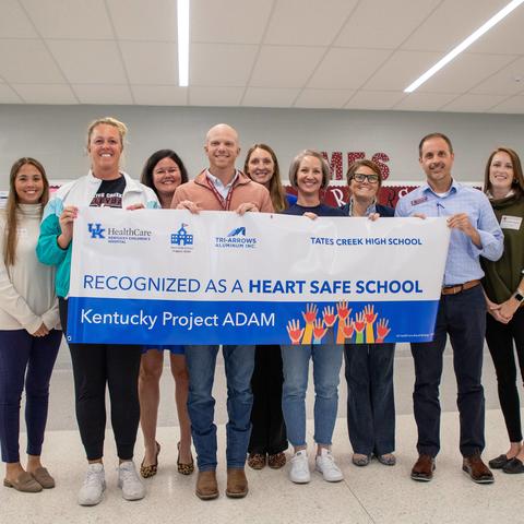 a group of educators from Tates Creek high school hold a banner recognizing their heart safe school status