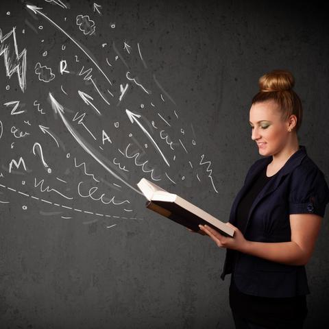 photo of woman with book open and drawings on chalkboard appearing to rise from it