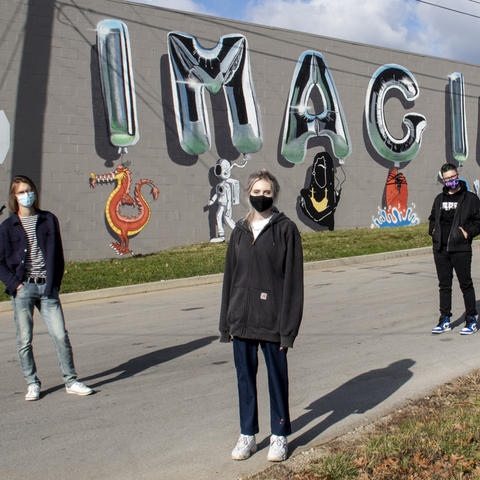 photo of 3 Guerilla Art students with "Imagine Nation" mural