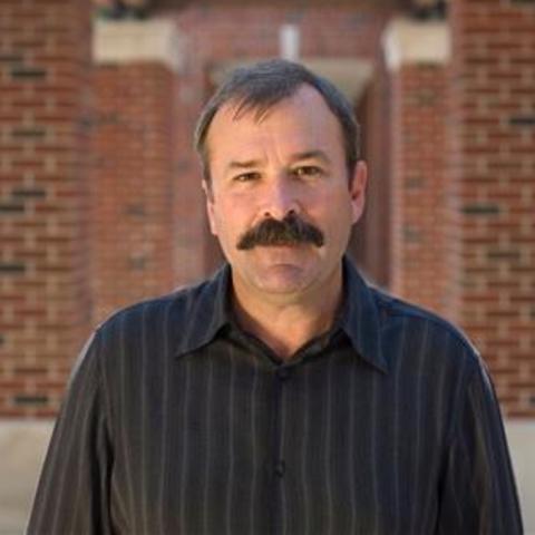 photo of James Campbell standing between 2 rows of brick columns