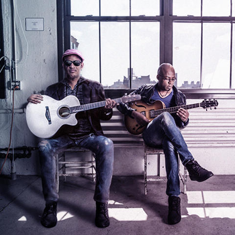 photo of Raul Midon and Lionel Lueke with their guitars seated on bench