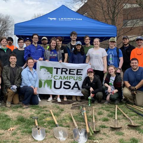 photo of group of people prior to a tree planting and a sign that says Tree Campus USA.